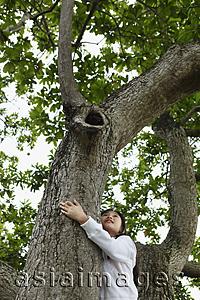 Asia Images Group - Young girl hugging a tree