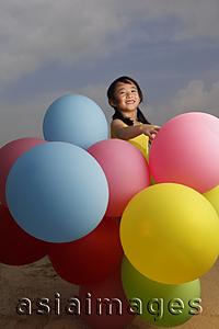 Asia Images Group - Young girl smiling at camera holding balloons.