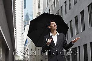 Asia Images Group - businessman holding umbrella, looking up into the sky