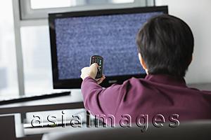 Asia Images Group - Back shot of man watching TV and holding remote