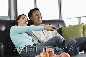 Asia Images Group - Young couple watching TV and laughing