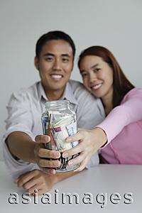 Asia Images Group - Young couple holding jar of money