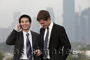 Asia Images Group - Chinese man talking on phone while Caucasian man texts.