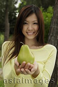 Asia Images Group - Young woman holding a yellow pear
