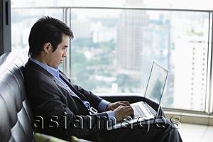 Asia Images Group - Profile of man using laptop in front of window