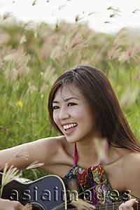 Asia Images Group - smiling woman playing guitar outside