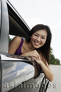 Asia Images Group - young woman leaning out of car window smiling