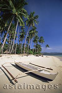 Asia Images Group - Philippines,Palawan,Bascuit Bay,El Nido,Couple Sunbathing on Beach with Outrigger Boat in Foreground