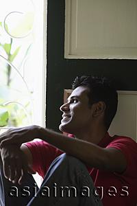 Asia Images Group - Indian man looking out window and smiling