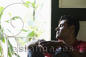 Asia Images Group - Indian man sitting near window with closed eyes