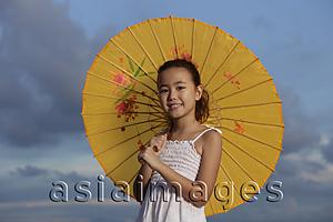 Asia Images Group - young girl holding yellow Chinese umbrella and smiling