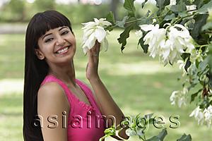 Asia Images Group - Smiling woman with long hair, holding flowers