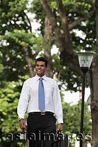 Asia Images Group - Indian man walking outside holding briefcase and smiling