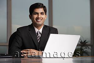 Asia Images Group - Indian man sitting at table with laptop