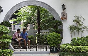 Asia Images Group - Two men sit inside circular door of park. Hong Kong