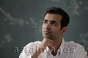 Asia Images Group - Head shot of young man with hand on his chin looking up