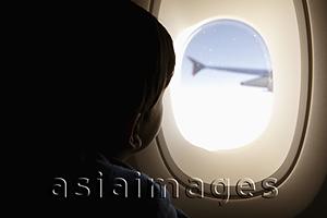 Asia Images Group - Young boy looking out of plane window