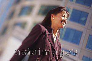 Asia Images Group - Female executive with office building behind, low angle view