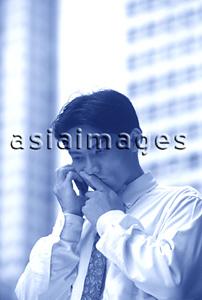 Asia Images Group - Male executive using cellular phone, thoughtful expression
