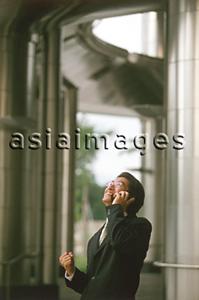 Asia Images Group - Male executive talking on cellular phone, office building behind