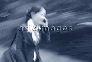Asia Images Group - Female executive talking on cellular phone (motion blur)