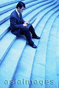 Asia Images Group - Male executive sitting on steps using laptop