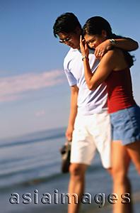 Asia Images Group - Young couple walking on beach, embracing