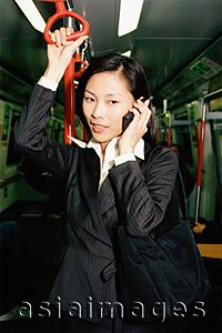 Asia Images Group - Female executive in subway train, talking on cellular phone