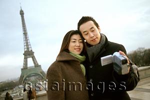 Asia Images Group - Couple videotaping themselves in front of Eiffel Tower.