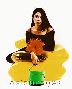 Asia Images Group - Young woman sitting on yellow inflatable chair, holding green purse