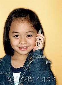 Asia Images Group - Young girl using cellular phone, portrait, yellow background.