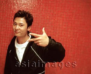 Asia Images Group - Young man gesturing, orange/red background.