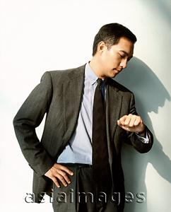 Asia Images Group - Male executive looking at watch against white background.