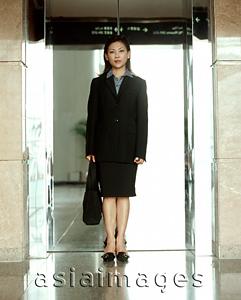 Asia Images Group - Executive woman standing in front of reflective elevator doors, portrait.
