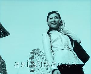 Asia Images Group - Woman on cellular phone, ferris wheel in background.