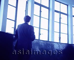 Asia Images Group - Executive with back to camera looking out window.