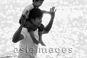 Asia Images Group - Father and son wading in water, son on father's shoulders