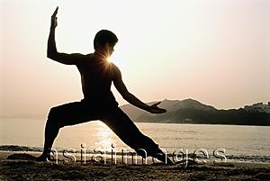 Asia Images Group - Silhouette of man doing Kung Fu moves at beach