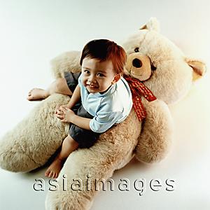 Asia Images Group - Young boy sitting on teddy bear