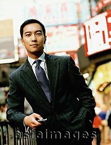 Asia Images Group - Portrait of executive holding cellular phone on street.