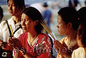 Asia Images Group - Cambodia, Phnom Penh, Worshippers praying with incense at a temple.