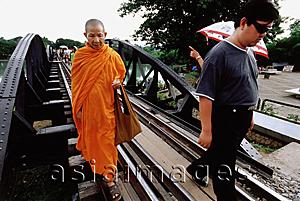 Asia Images Group - Thailand, Kanchanaburi, River Kwai, A monk walking over the bridge, along with other tourists.