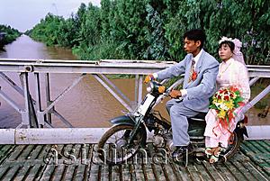Asia Images Group - Vietnam, Mekong Delta region, Long Xuyen, Bride and groom on moped crossing bridge.