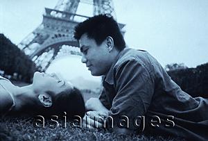Asia Images Group - Young couple lying on grass, Eiffel Tower in background.