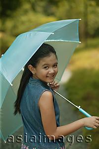 Asia Images Group - Young girl holding an umbrella, looking over shoulder