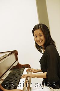 Asia Images Group - Woman at piano, looking at camera