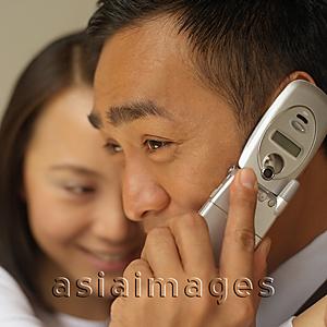Asia Images Group - Businessman on mobile phone, woman in the background