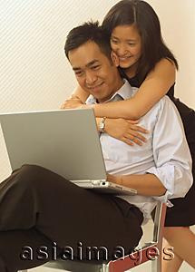 Asia Images Group - Man using laptop, woman hugging him