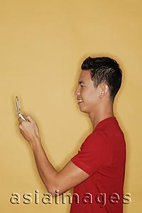 Asia Images Group - Young man holding mobile phone, profile