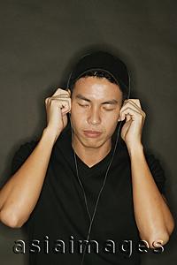 Asia Images Group - Young man using headphones, black background